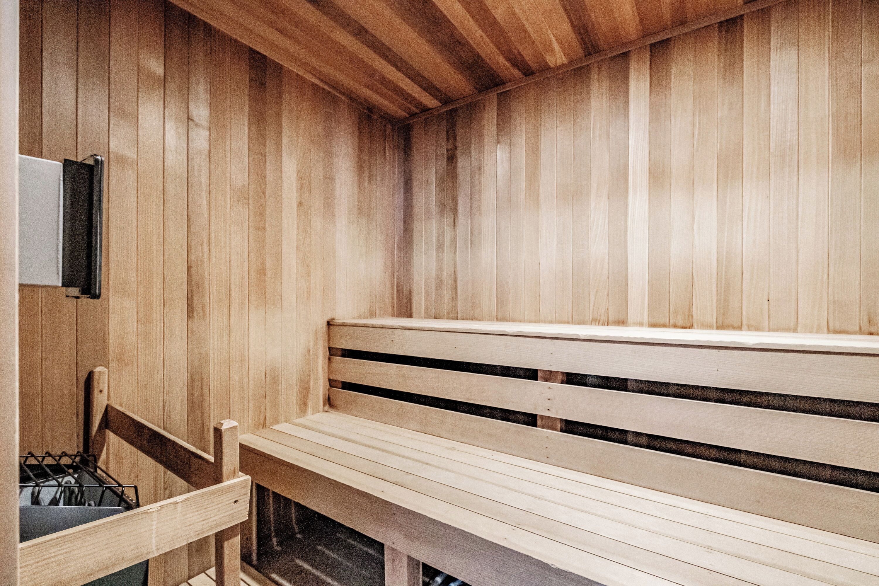 A wooden sauna with benches and a wall-mounted heater.