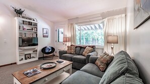 A living room with a sofa, a coffee table, a bookshelf, and a TV.
