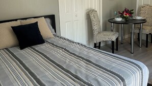 Une chambre à coucher avec un grand lit, une petite table ronde avec des chaises et une porte ornée d’un panneau décoratif.