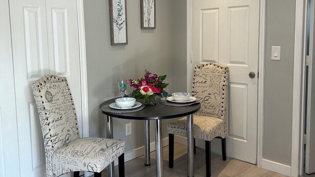 Un coin repas comprenant deux chaises, une table et un vase de fleurs.