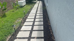 Un chemin bordé de dalles carrées menant à un bâtiment.