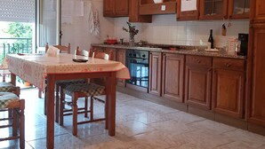 A kitchen with wooden cabinets, a dining table with chairs, a ceiling fan, and a window with blinds.