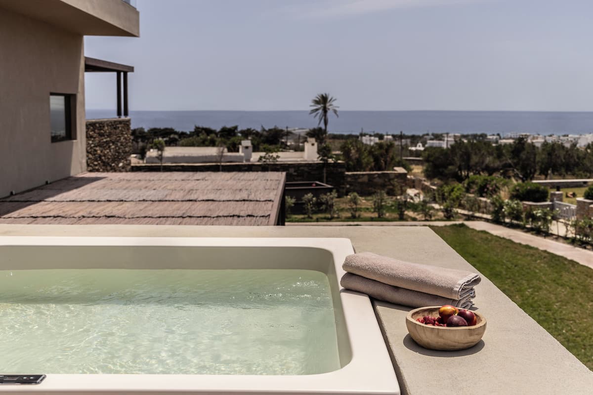 A hot tub with a clear view of the ocean and a bowl of fruit on the side.