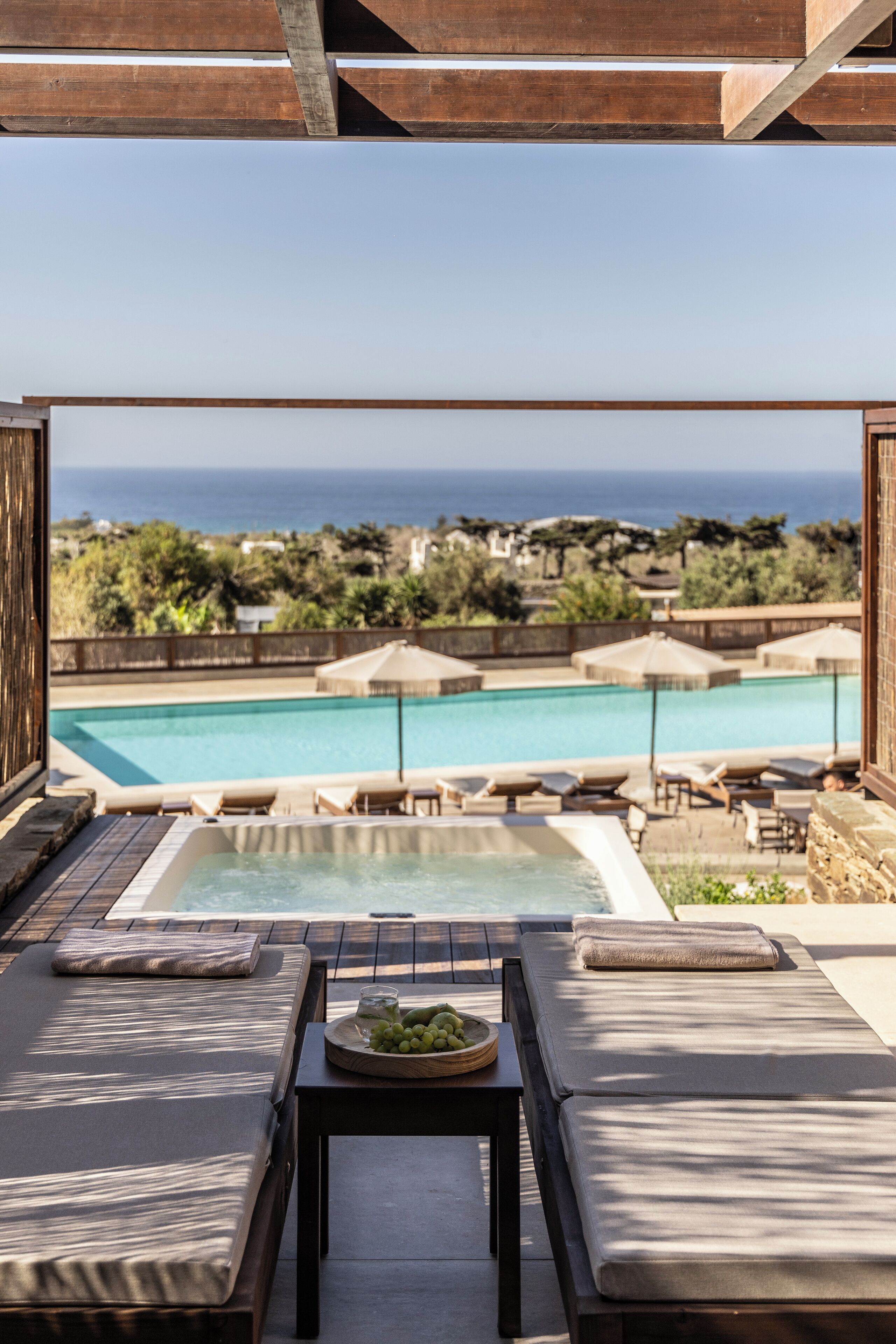 A poolside area with a hot tub, lounge chairs, and a view of the ocean.