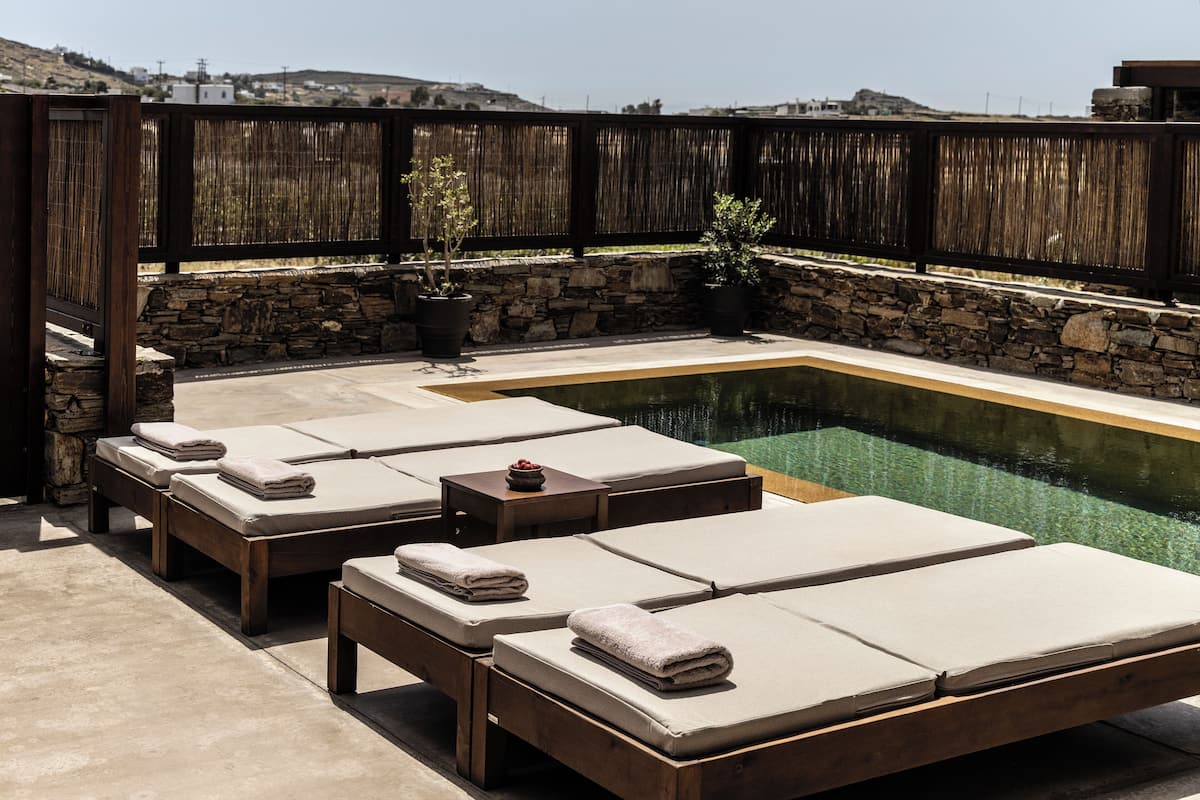 A poolside area with lounge chairs and a stone wall.