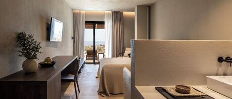 A modern hotel room with a bed, a desk, a TV, and a view of the city.