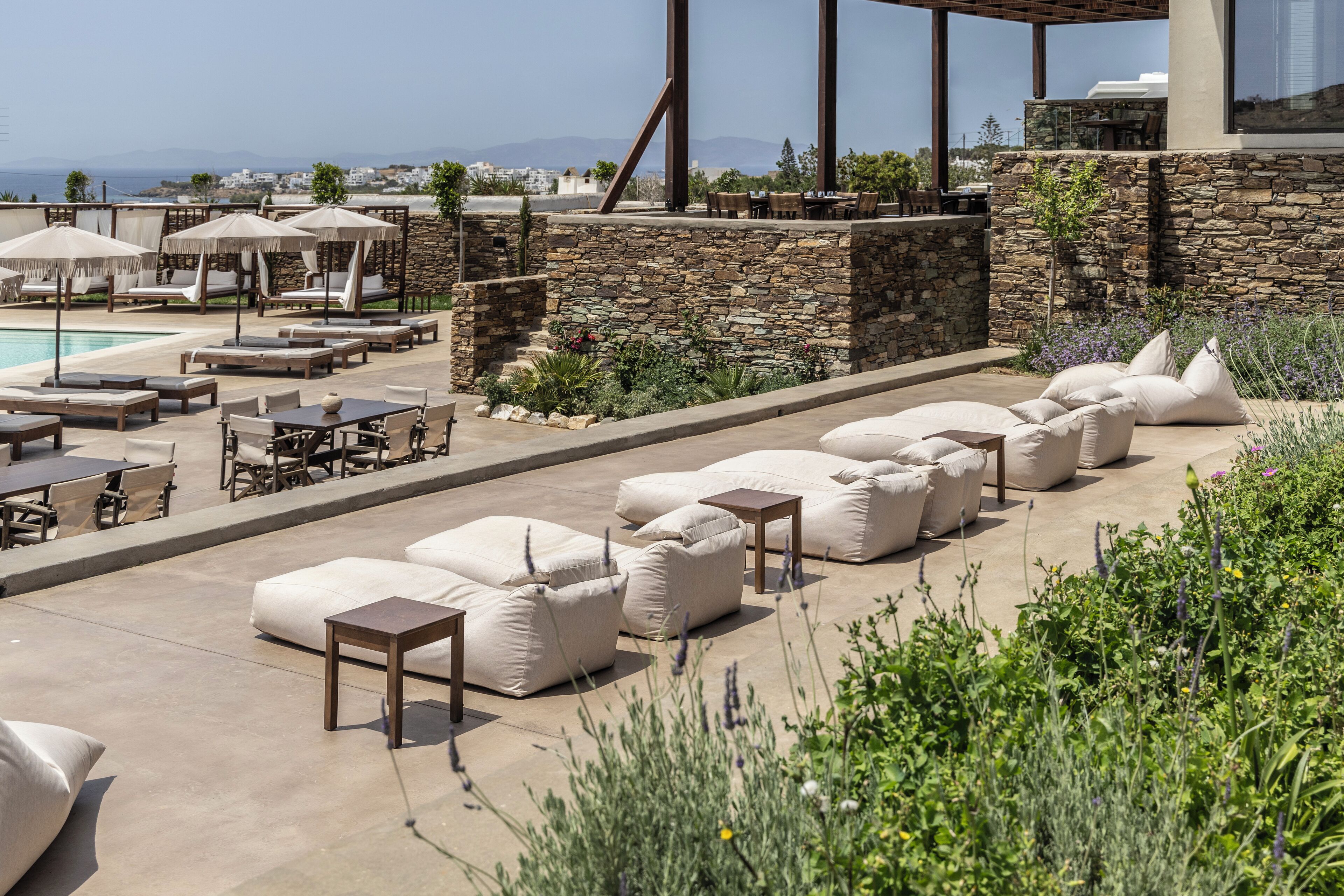 A rooftop pool area with lounge chairs, tables, and umbrellas.