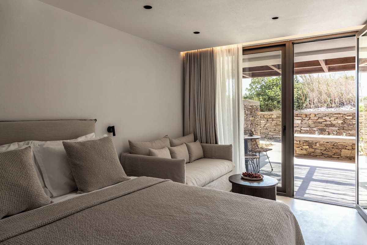 A modern bedroom with a large bed, a sofa, and a dining table.