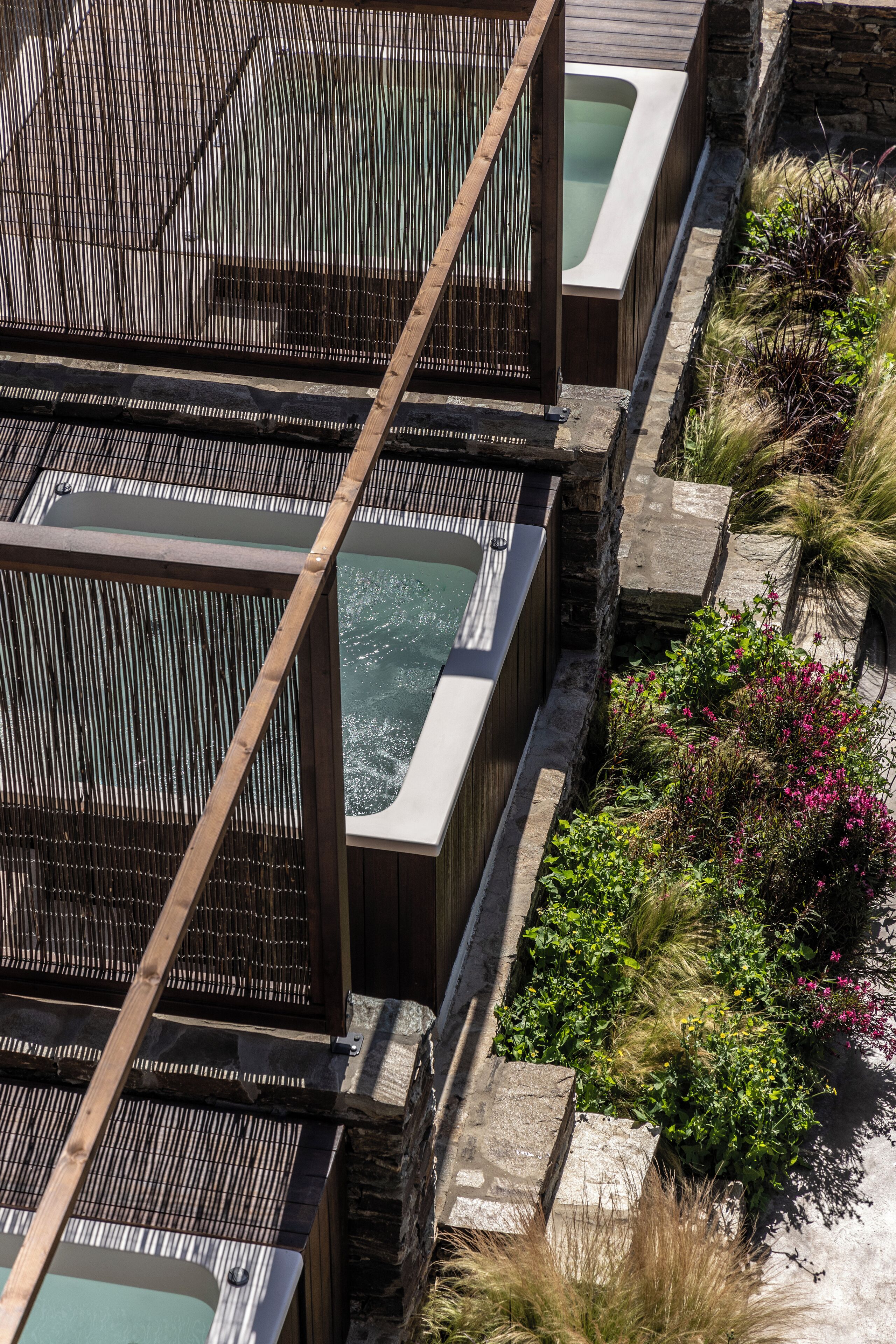 A spa area with multiple hot tubs, wooden railings, and a stone wall.