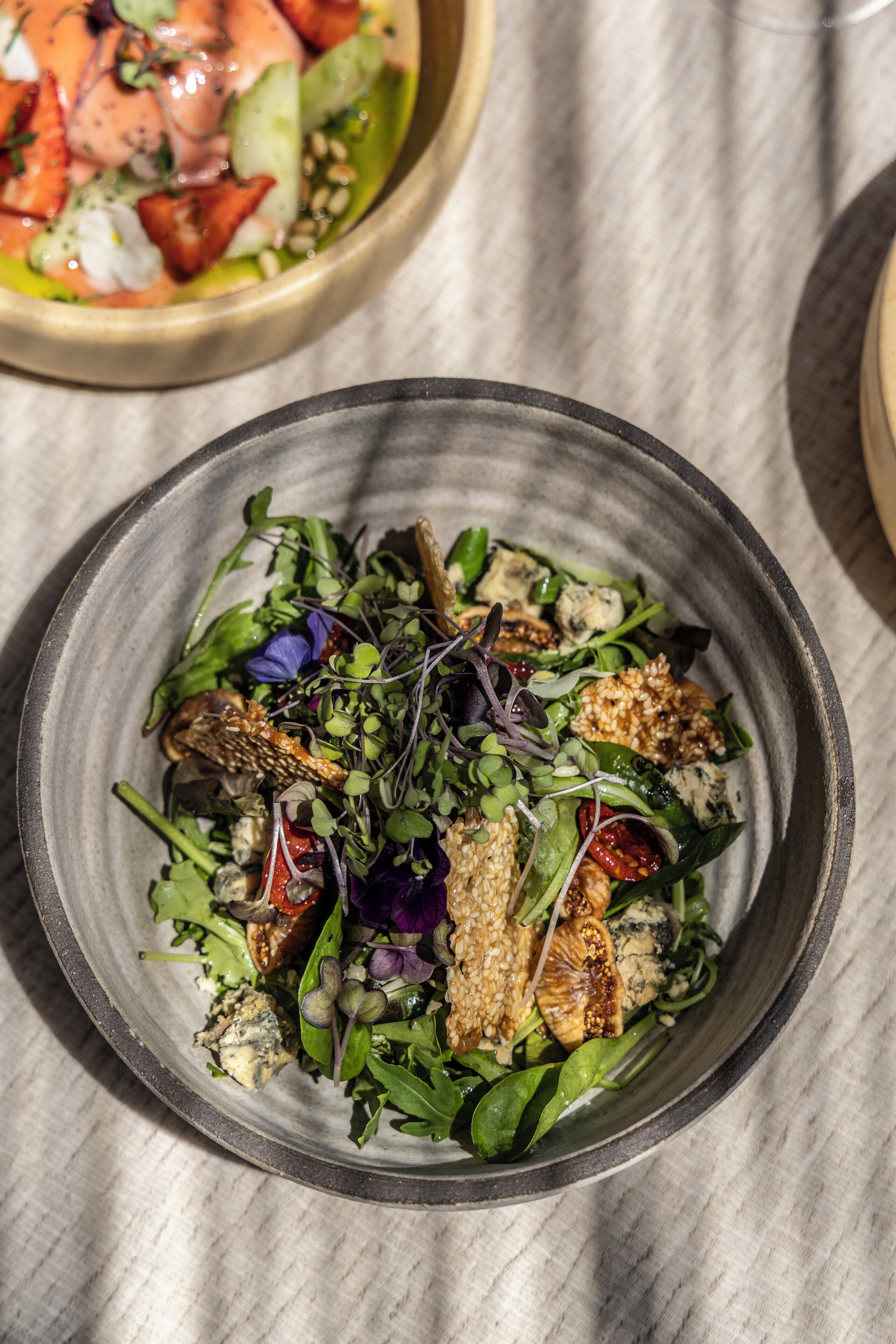A bowl of salad with various greens and toppings.