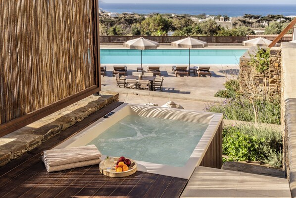 Tinaco con vista a la piscina, sillas de descanso y una cesta de frutas.