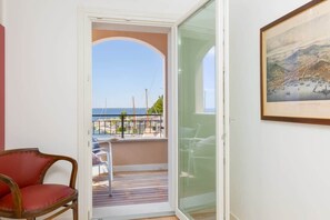 Una habitación con vistas al mar, un cuadro enmarcado en la pared y una silla roja.