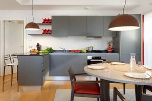 Cocina moderna con armarios grises, una isla central e iluminación colgante.