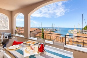 Un balcón con mesa lista para el desayuno, con vistas a una marina con barcos y edificios.