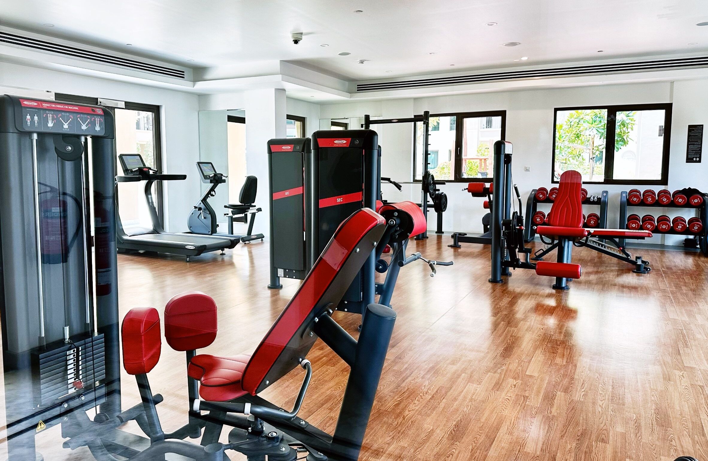 A gym with cardio machines, weightlifting equipment, and dumbbells.