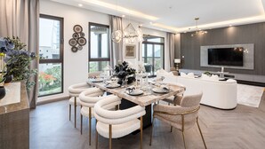 A modern living room with a dining area, a large TV, and a view of the outdoors. - Lamtara 1 - Mint Stay (Dubai)