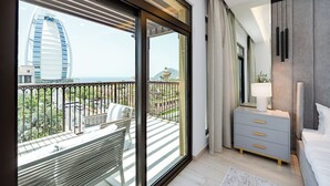 A modern bedroom with a balcony, a bed, a nightstand, and a view of a cityscape. - Lamtara 1 - Mint Stay (Dubai)