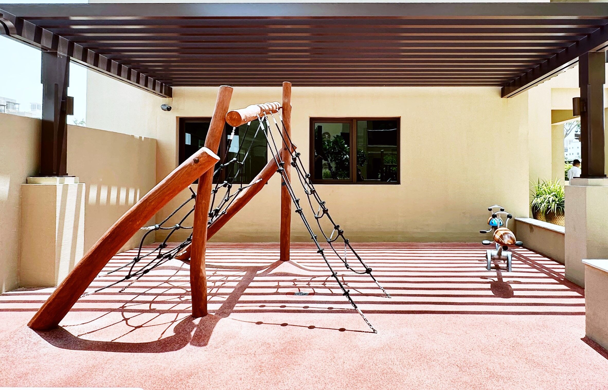 A covered outdoor area with a wooden climbing structure and a scooter.
