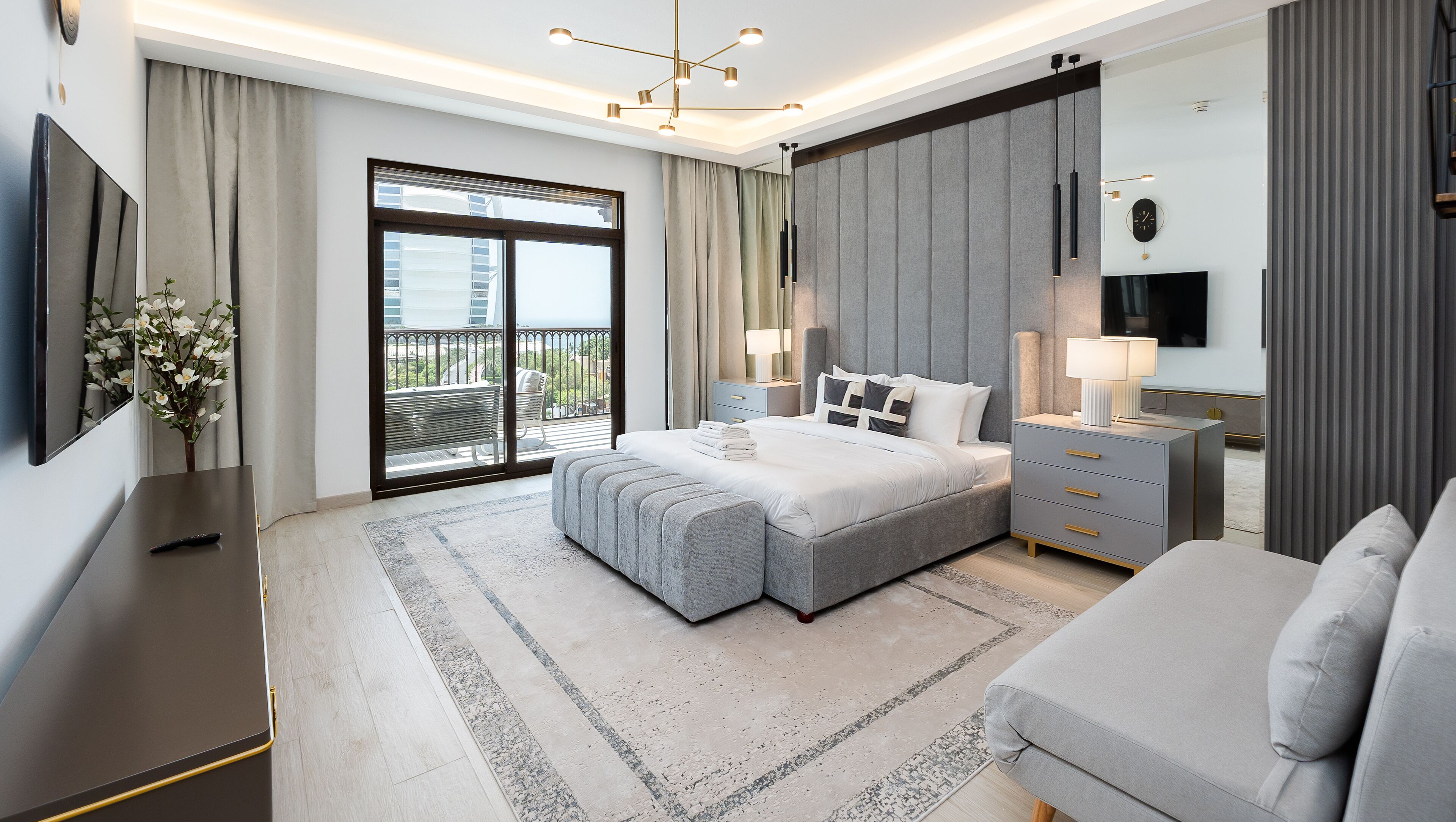 Un dormitorio moderno con una cama grande, un televisor de pantalla plana, un escritorio y un balcón con vistas.