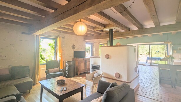 Ein rustikales Wohnzimmer mit freiliegenden Holzbalken, einem Kamin, einer Couch und einem Essbereich mit Tisch und Stühlen.
