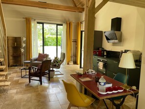 Relax in this open-plan living space with a dining area, featuring a sofa, armchairs, and dining table.