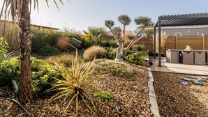 Un jardin où l’on trouve une variété de plantes, un palmier et une clôture en bois.