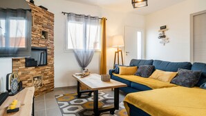 Un salon moderne avec un canapé, un téléviseur, un mur en bois et une lampe.