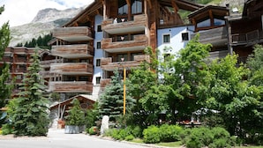 A multi-story wooden building with balconies, surrounded by greenery and mountains. - Luxury Duplex in Val-d'Isère with Jacuzzi and Hammam (Val-d'Isère)