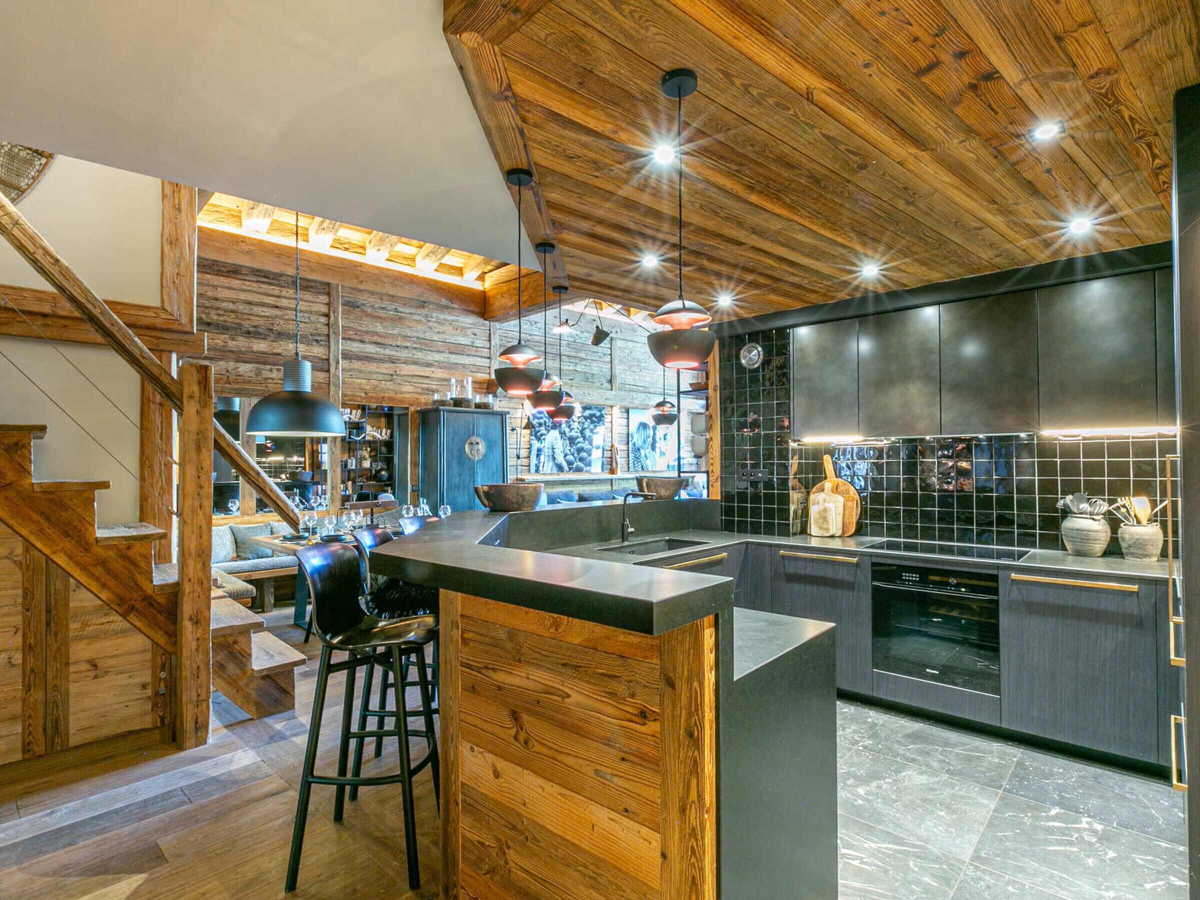 Una cocina moderna con techo de madera, barra y zona de comedor con taburetes.