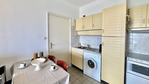 A compact kitchen with a washing machine, a sink, and a stove.