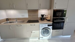 Una cocina moderna con lavadora integrada, cafetera y horno Bosch.