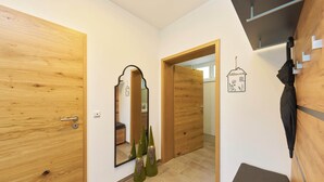 Ein Flur mit Holztüren, einem Spiegel, einer kleinen Bank und einem an der Wand befestigten Regenschirm.
