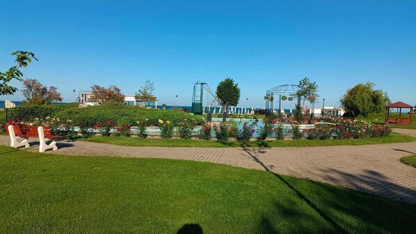 Un parque con un estanque, bancos y un pabellón.