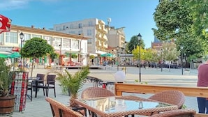 Ein Café im Freien mit Korbmöbeln, Blumentöpfen und blauem Himmel.