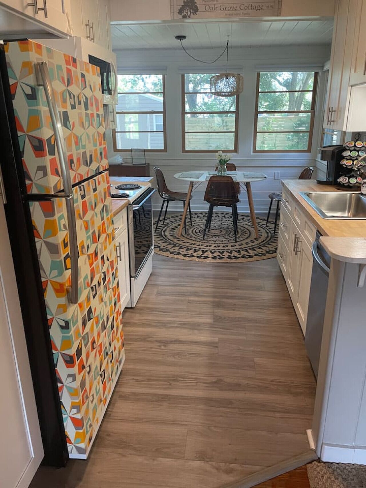 Une cuisine avec un réfrigérateur à motifs, une table à manger avec des chaises et un tapis.