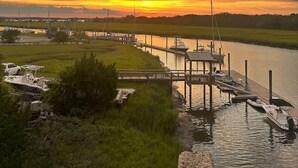 Un port de plaisance avec des bateaux amarrés, une jetée s’avançant dans l’eau et un coucher de soleil en arrière-plan.