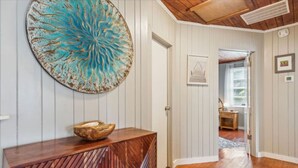 Un couloir doté d’un plancher en bois, d’un élément décoratif mural et d’une console en bois sur laquelle est posé un bol.