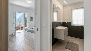 A modern bedroom with a large window, a bed, and a view of mountains. - Casa Beatrice (Tenno)