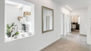 A modern hallway with a large mirror, potted plants, and a clean, minimalist design. - Casa Beatrice (Tenno)