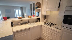 A kitchen with white cabinets, a sink, a stove, and a microwave. - Duplexe with panoramic south-facing terrace in the center of Grimaud (Grimaud)