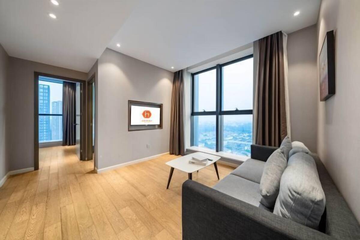 A modern living room with a sofa, a coffee table, and a large window offering a city view.