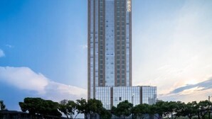 A tall, modern building with a glass facade and a shorter structure in front. - Huanlesong Hotel (Jiaxing Zhongguancun Wanli Square) (Jiaxing)