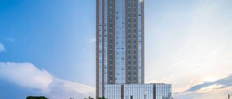 A tall, modern building with a glass facade and a shorter structure in front.