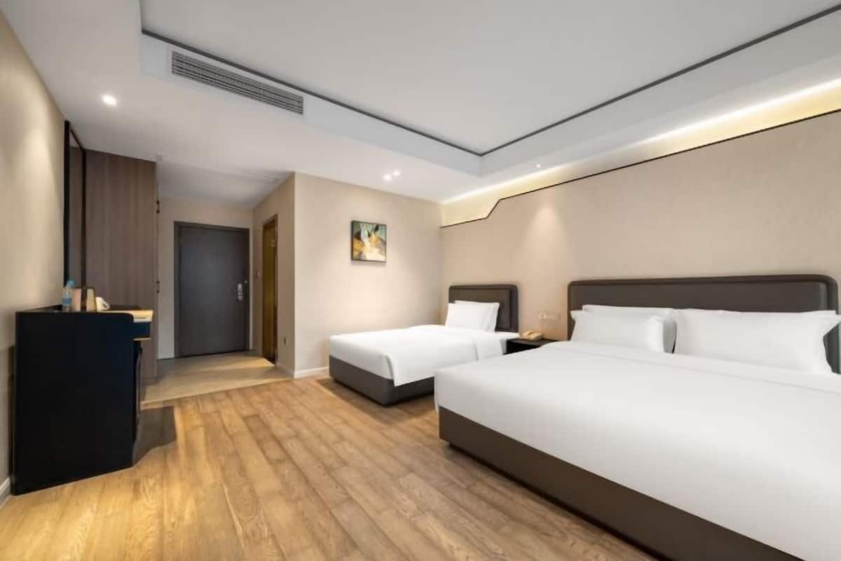A hotel room with a large bed, a smaller bed, a desk, and a door.