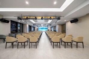 A conference room with rows of chairs facing a stage, equipped with lighting and audio systems. - Huanlesong Hotel (Jiaxing Zhongguancun Wanli Square) (Jiaxing)