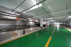 A multi-level parking garage with marked parking spaces, overhead lighting, and structural beams. - Huanlesong Hotel (Jiaxing Zhongguancun Wanli Square) (Jiaxing)