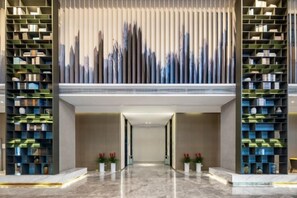 Un hall d’entrée moderne avec une allée centrale bordée de hautes étagères.