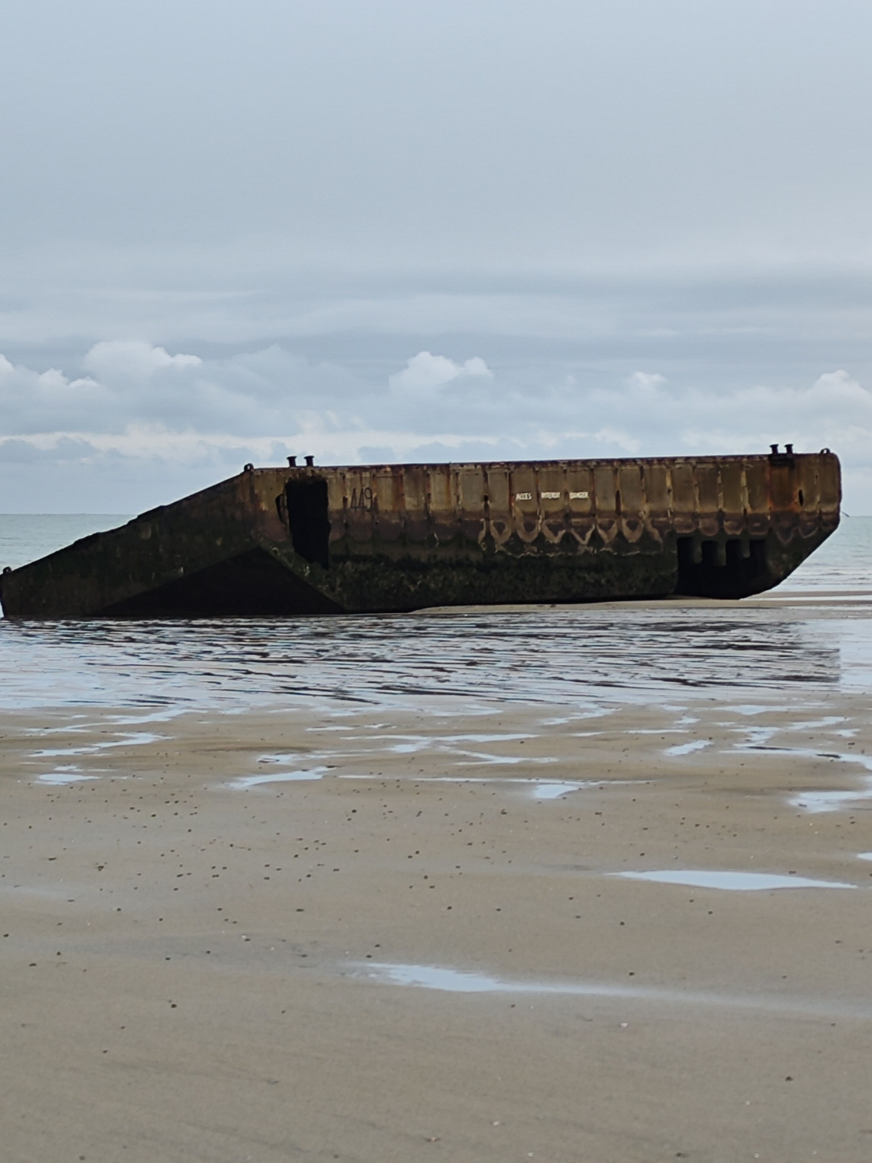 Een groot, verroest wrak aan het strand.