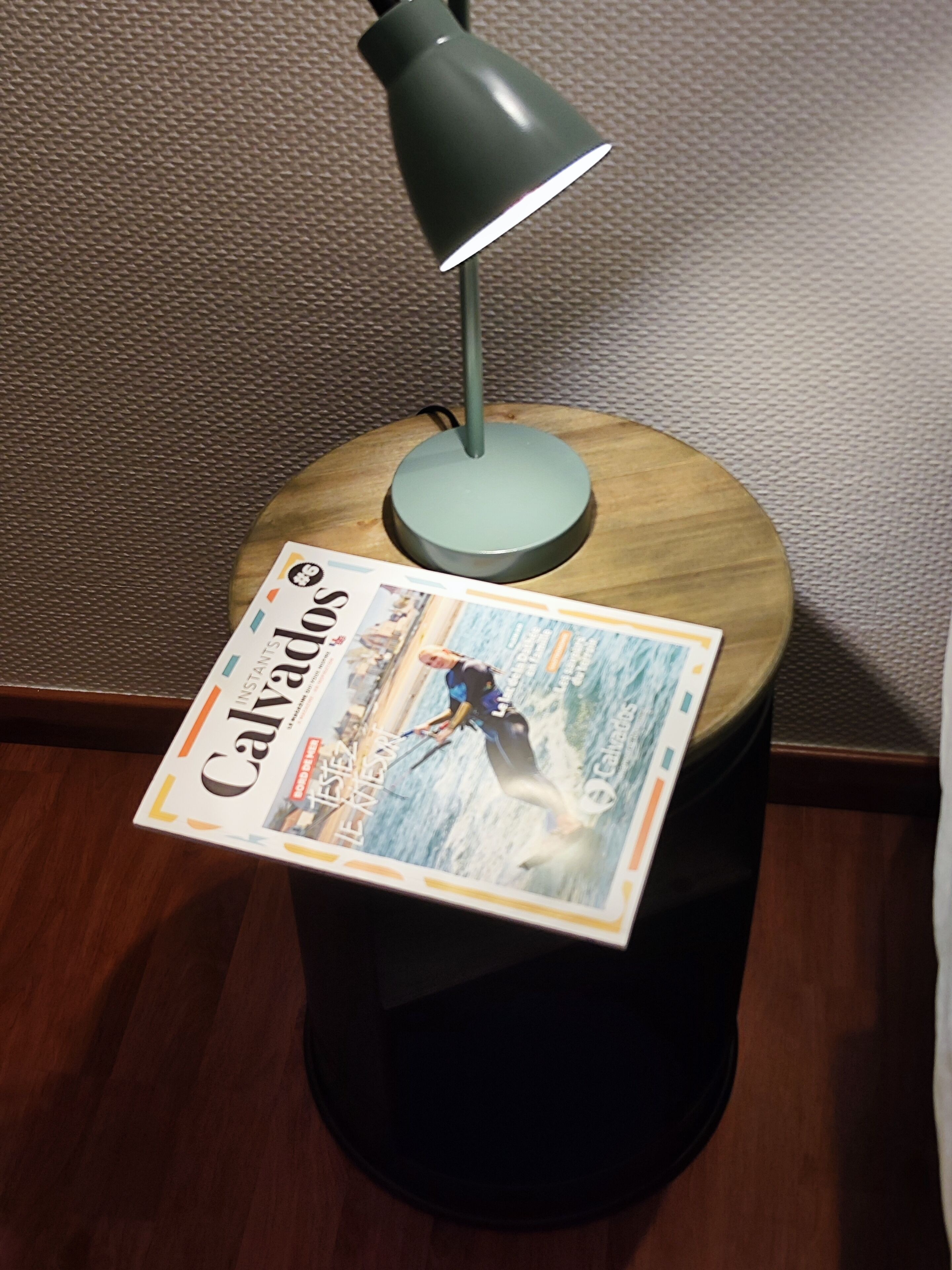 Una revista sobre una mesa de madera con una lámpara.