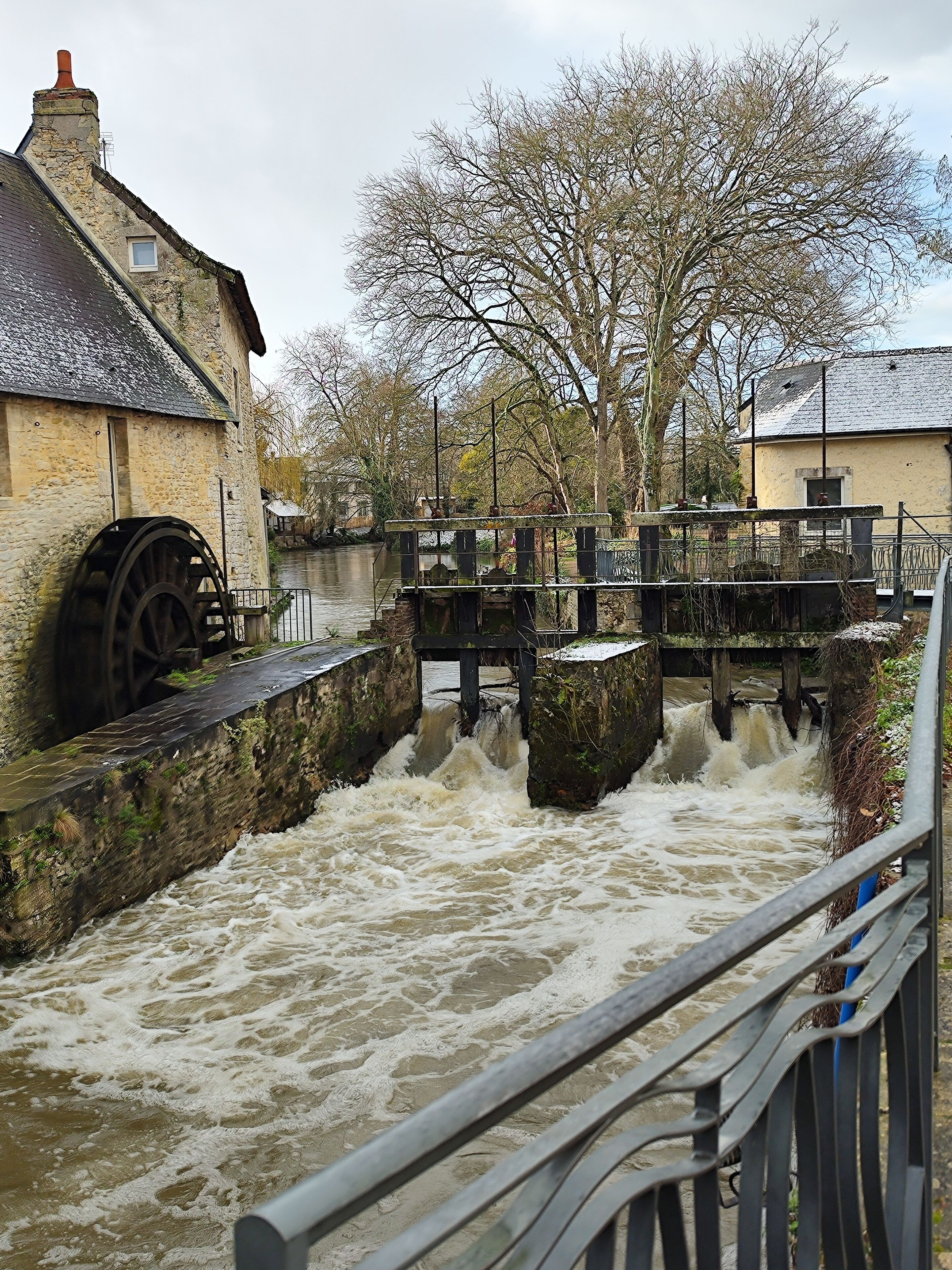 A water mill with a wooden structure and a stone building nearby.